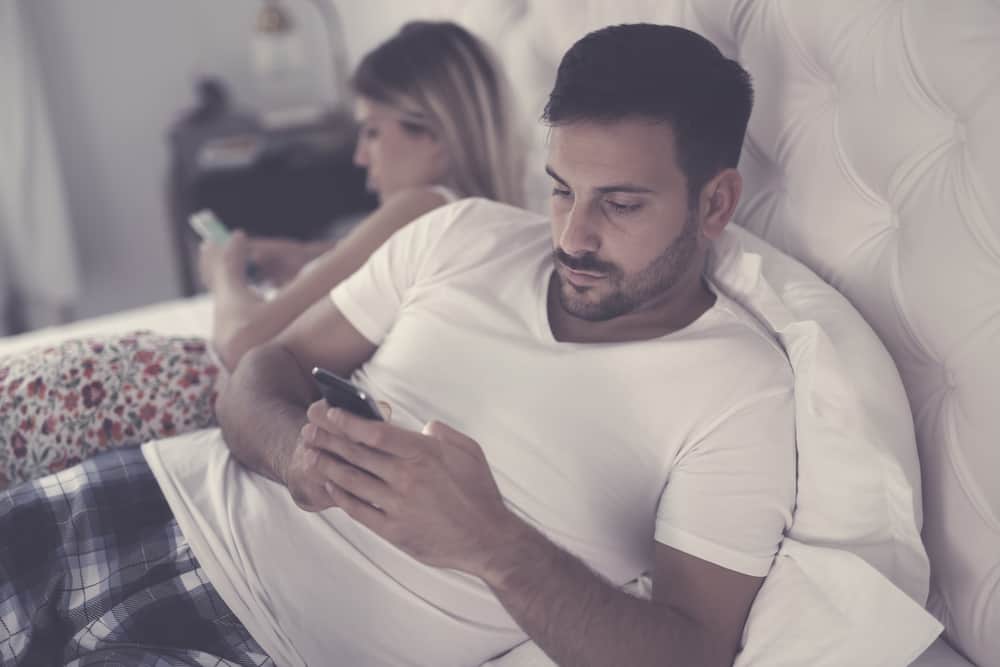 Man and woman facing separate ways, focused on their phones.