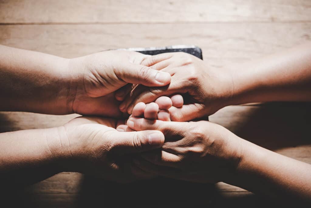 Close up of people holding hands.