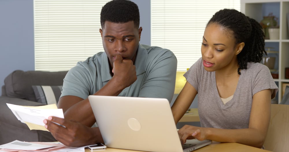 A man has a distraught face while a woman is on her laptop.