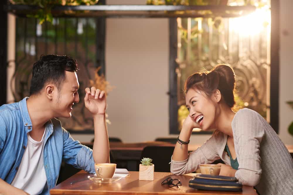 A man and woman laugh while at a cafe.
