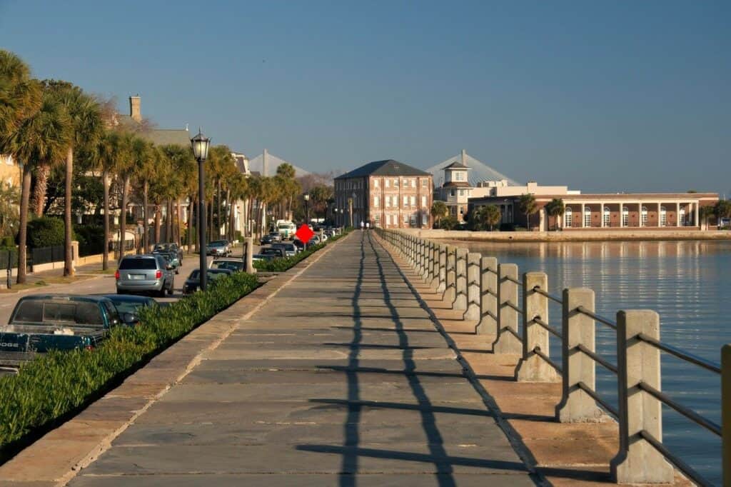An empty walkway along the waterfront under a blue sky.