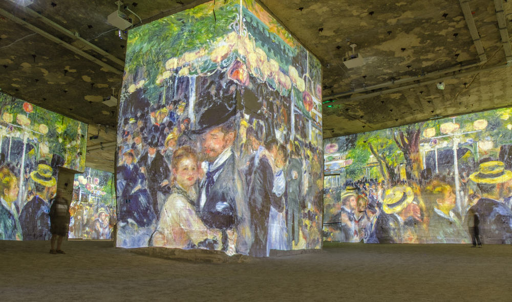 A large pillar in the middle of a room where all of the walls are covered with famous artwork. 